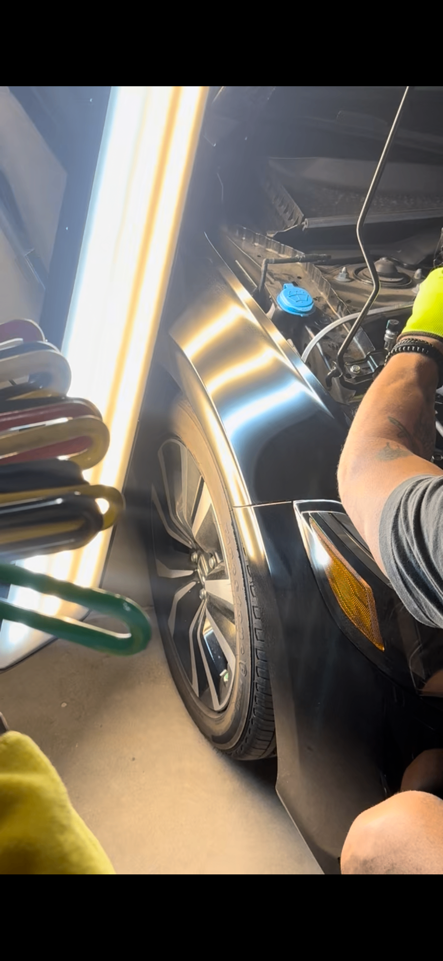 Hailology technician inspecting a repaired panel under a calibrated reflective PDR lighting board to reveal remaining imperfections